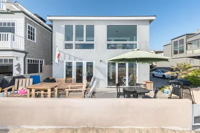 a house with a patio with a table and an umbrella at Renovated 3Br Oceanfront W Panoramic Views By Beachview Rentals in Newport Beach