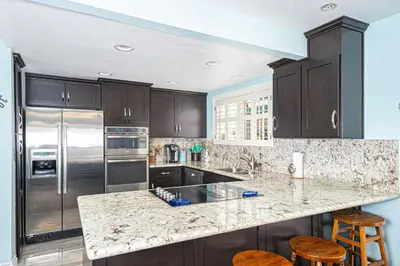 a kitchen with a granite counter top and stainless steel appliances at Roomy 2Br W Large Patio, Fire Pit And Ocean Views By Beachview Rentals in Newport Beach