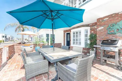 a patio with a table and chairs with an umbrella at Roomy 2Br W Large Patio, Fire Pit And Ocean Views By Beachview Rentals in Newport Beach