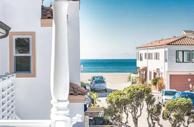 a view of the beach from the balcony of a house at Roomy 2Br W Large Patio, Fire Pit And Ocean Views By Beachview Rentals in Newport Beach