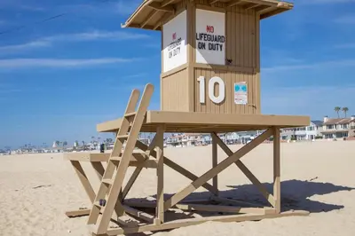 a lifeguard tower on the beach with a wooden bench at Quiet 1Br Bayside Apartment, Central, Steps To Baybeach By Beachview Rentals in Newport Beach