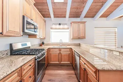 a kitchen with wooden cabinets and a stove top oven at 6Br Oceanfront Duplex, Ac, Steps To Beach And Balboa Pier By Beachview Rentals in Newport Beach