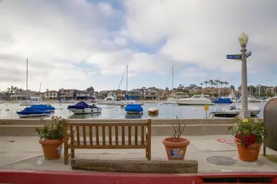 a wooden bench sitting next to a marina with boats at Updated 1Br Bayfront Cottage W Deck In Quiet Balboa Island By Beachview Rentals in Newport Beach
