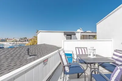 a patio with chairs and a table on a roof at Updated 1Br Bayfront Cottage W Deck In Quiet Balboa Island By Beachview Rentals in Newport Beach