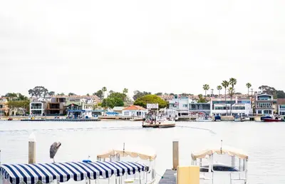 a dock with a boat in the water with houses at Updated 1Br Bayfront Cottage W Deck In Quiet Balboa Island By Beachview Rentals in Newport Beach
