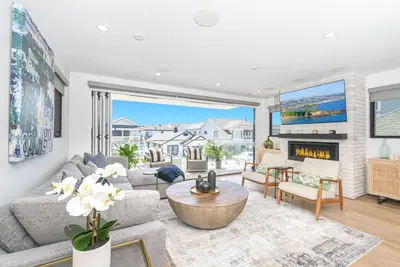 a living room with a couch and a fireplace at Luxe 3Br Near The Sand W Rooftop Spa, Ocean Views, And Ac By Beachview Rentals in Newport Beach