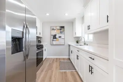 a kitchen with white cabinets and a stainless steel refrigerator at Remodeled 2Br, One House From Beach, Walk To Shopsdining By Beachview Rentals in Newport Beach
