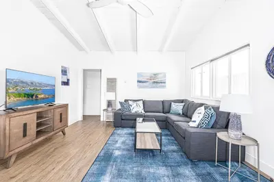 a living room with a couch and a tv at Stylish 2Br Cottage W Large Patio, One House From The Sand By Beachview Rentals in Newport Beach