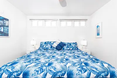 a bedroom with a blue and white bed with two lamps at Stylish 2Br Cottage W Large Patio, One House From The Sand By Beachview Rentals in Newport Beach