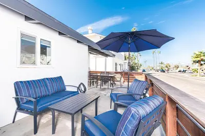 a patio with chairs and a table and an umbrella at Stylish 2Br Cottage W Large Patio, One House From The Sand By Beachview Rentals in Newport Beach