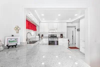a kitchen with white cabinets and a counter top at Serene 3Br Bayside Home, Private Waterfront Dock And Patio By Beachview Rentals in Newport Beach