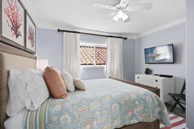 a bedroom with a bed with a ceiling fan and a window at Elegant 6Br Oceanfront W Rooftop Deck And Stunning Views By Beachview Rentals in Newport Beach