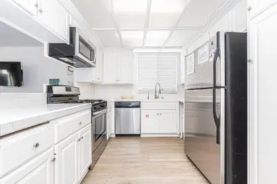 a kitchen with white cabinets and a stainless steel refrigerator at Epic 7Br Retreat W Oceanview Rooftop Deck - Steps To Sand By Beachview Rentals in Newport Beach