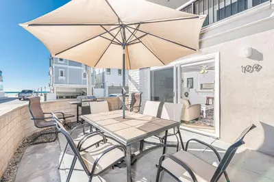 a table and chairs with an umbrella on a patio at Epic 7Br Retreat W Oceanview Rooftop Deck - Steps To Sand By Beachview Rentals in Newport Beach