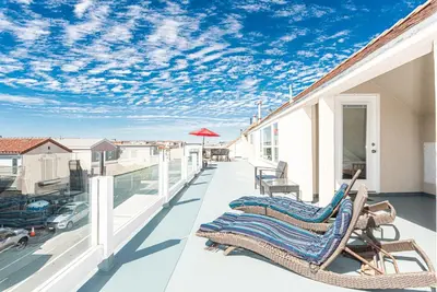 a balcony with two chairs and an umbrella at Epic 7Br Retreat W Oceanview Rooftop Deck - Steps To Sand By Beachview Rentals in Newport Beach