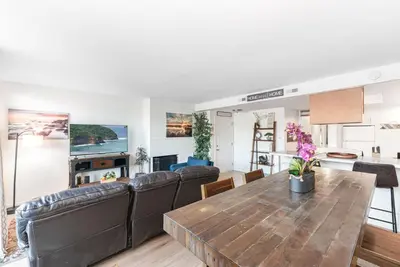 a dining room and living room with a wooden table at Cozy And Central 3Br, Steps From Sand And Marina Park By Beachview Rentals in Newport Beach