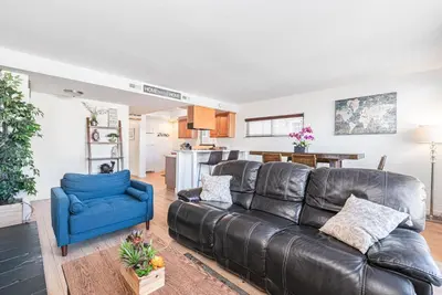 a living room with a leather couch and a blue chair at Cozy And Central 3Br, Steps From Sand And Marina Park By Beachview Rentals in Newport Beach