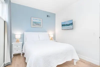 a white bedroom with a white bed and two lamps at Spacious 7Br Triplex Steps From Beach And Marina Park By Beachview Rentals in Newport Beach