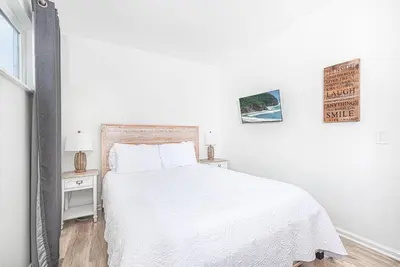 a white bedroom with a white bed and a window at Spacious 7Br Triplex Steps From Beach And Marina Park By Beachview Rentals in Newport Beach
