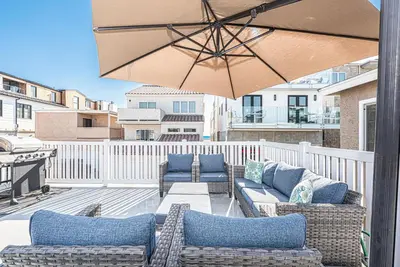 a patio with couches and an umbrella on a balcony at Spacious 7Br Triplex Steps From Beach And Marina Park By Beachview Rentals in Newport Beach