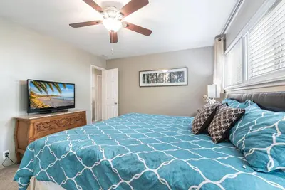 a bedroom with a blue bed and a ceiling fan at Peaceful Lido Island 3Br, Walk To Bay, Beach And Shopping By Beachview Rentals in Newport Beach