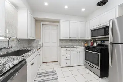 a kitchen with white cabinets and a black refrigerator at Peaceful Lido Island 3Br, Walk To Bay, Beach And Shopping By Beachview Rentals in Newport Beach