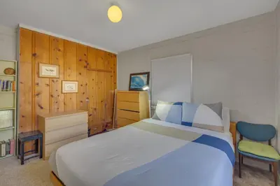 a bedroom with a large bed and a chair at 2 Blocks to Beach, Firepit, Sandbox, BBQ, Work in Carlsbad