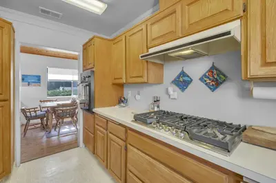 a kitchen with wooden cabinets and a stove top oven at 2 Blocks to Beach, Firepit, Sandbox, BBQ, Work in Carlsbad