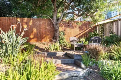 a garden with a tree and a wooden walkway at San Diego Staycation Home with Hot Tub Ocean Views in Encinitas