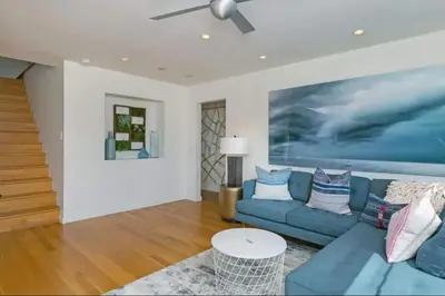 a living room with a blue couch and a ceiling fan at Sunset Cliffs Dream Home Ocean View Family Getaway in San Diego