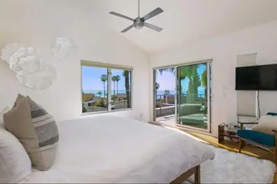 a white bedroom with a large bed and a flat screen tv at Sunset Cliffs Dream Home Ocean View Family Getaway in San Diego