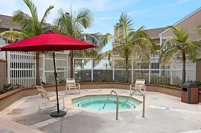 a red umbrella and chairs next to a swimming pool at Chic Upstairs Condo Steps from Strands Beach in Dana Point
