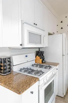 a white kitchen with a stove and a microwave at Pacific Beach Cottage 1 Walk to the Beach and Bay in San Diego