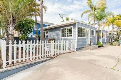 a blue house with a white fence and palm trees at Pacific Beach Cottage 1 Walk to the Beach and Bay in San Diego