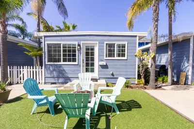 a blue house with chairs and a table in a yard at Pacific Beach Cottage 2 Walk to the Beach and Bay in San Diego