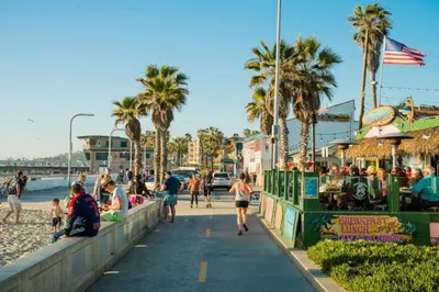 a group of people walking on a sidewalk next to the beach at Pacific Beach Cottage 2 Walk to the Beach and Bay in San Diego