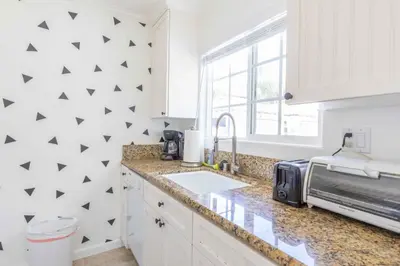 a white kitchen with a sink and a microwave at Pacific Beach Cottage 4 Walk to the Beach and Bay in San Diego