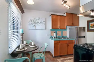 a kitchen with a table and chairs and a refrigerator at Cute Old Town Cottage near Downtown Beaches in San Diego