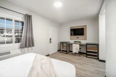 a bedroom with a bed and a desk and a tv at ERTH INN by AGA- San Ysidro in San Diego