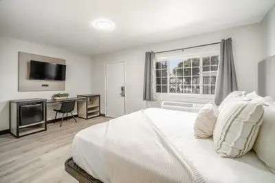 a bedroom with a bed and a desk and a television at ERTH INN by AGA- San Ysidro in San Diego