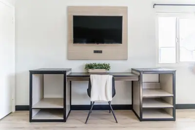 a desk with a television on a wall with a chair at ERTH INN by AGA- San Ysidro in San Diego
