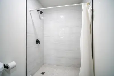a bathroom with a shower with a glass door at ERTH INN by AGA- San Ysidro in San Diego