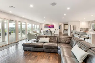 a living room with a leather couch and a kitchen at 2 Mi to Lake Poway Mtn-View Escape with Patio! in Poway