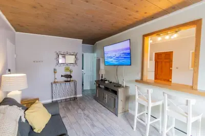 a living room with a couch and a tv on the wall at Cozy Ocean Beach Cottage Separate Entry in San Diego