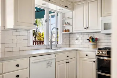 a white kitchen with white cabinets and a sink at The Whalen House - Steps from the Ocean in San Diego