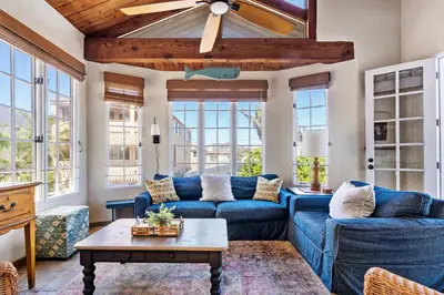 a living room with blue couches and a ceiling fan at The Whalen House - Steps from the Ocean in San Diego