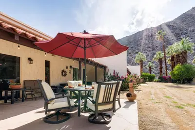 a patio with a table with a red umbrella at 2 Mi to Galleta Meadows Desert Golf Retreat! in Borrego Springs