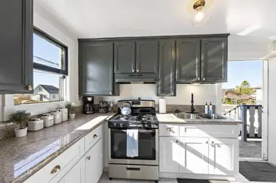a kitchen with white cabinets and black appliances at Victorian Gem Close to Petco Park & Gaslamp in San Diego