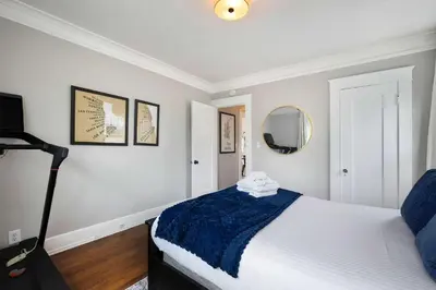 a bedroom with a bed with a blue blanket and a mirror at The Captain Quarters- Rosecrans Marina Escape in San Diego