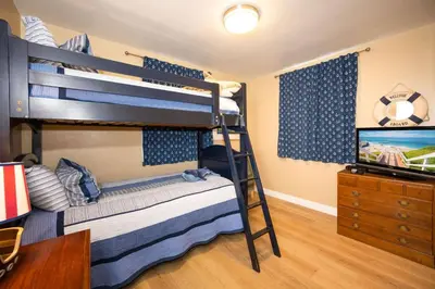 a bedroom with two bunk beds and a television at Steps from the Sand Mission Beach House in San Diego